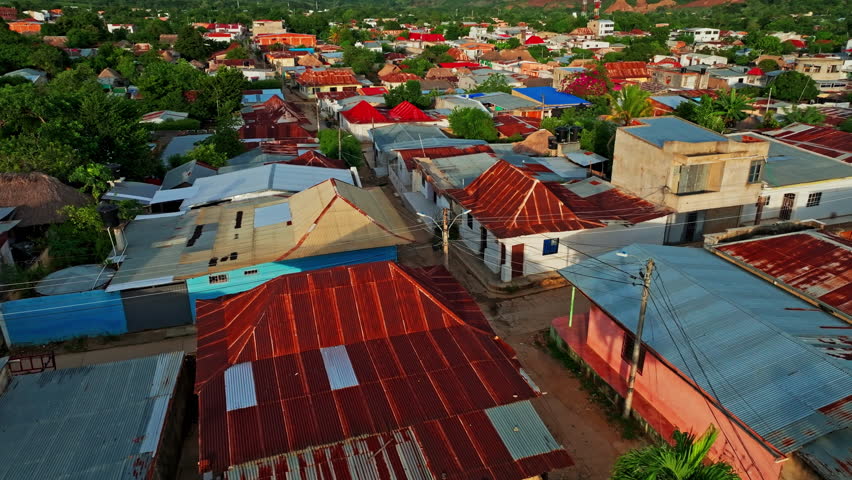 Aerial view over San Jacinto, Bolivar, Colombia, showing rooftops and streets bathed in golden light as the day transitions into evening.