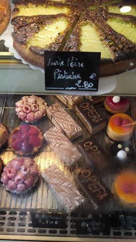 Delicious selection of fresh french pastries and cakes displayed in a bakery shop window. Various sweet desserts, including fruit tarts