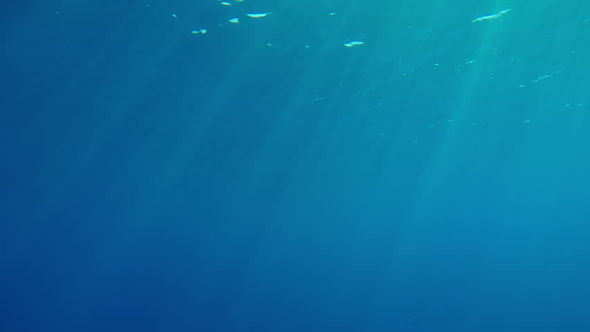 Bright rays of sun illuminates turquoise water of the Ocean, Slow motion of underwater sun light shines below water with ripples on waves surface, Underwater god rays in sea