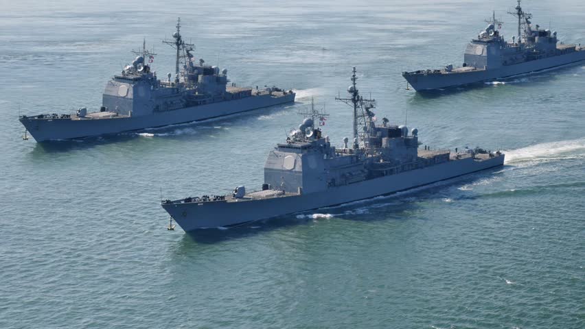 Group of modern naval warships sailing together in formation across open ocean waters. Concept of military power, naval fleet operations, maritime defense, and security patrol. Identifiable markings on ships removed. 15094