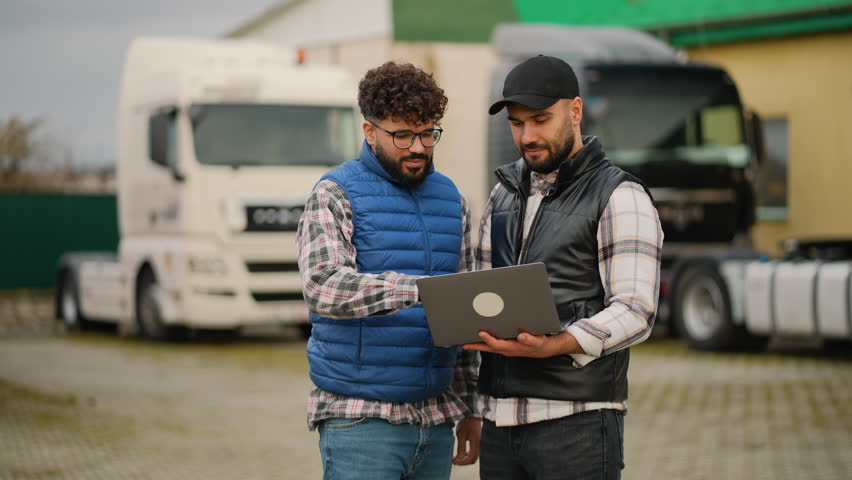 Truck drivers using laptop for logistics management