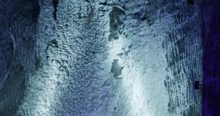 Close-up view of textured salt rock wall illuminated with blue light inside the underground chambers of the Salt Cathedral of Zipaquira.