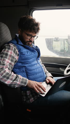 Professional truck driver using laptop in cabin