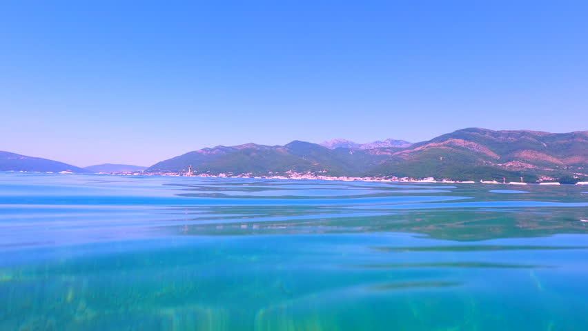 Calm turquoise adriatic sea gently lapping against the shores of montenegro. Crystal-clear turquoise water gently laps the coastline of montenegro, offering breathtaking views of the green mountains
