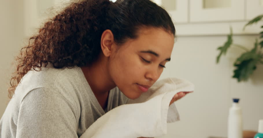 Cleaning face, dry and towel with woman in bathroom of home for hygiene or wellness routine. Grooming, skincare and washing with person in apartment, daily or morning cleansing with self care