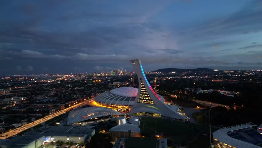 4K aerial drone hyperlapse of Montreal Olympic Stadium illuminated at night, a famous architectural landmark in Quebec, Canada.