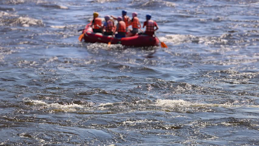 Rafting in whitewater, extreme water sports on water rapids, kayaking and canoeing tour in a mountain river,  water sports team, red and yellow raft boat full of tourists in a summer day, slow motion