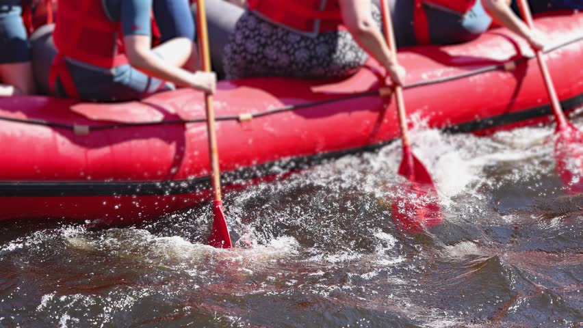 Rafting in whitewater, extreme water sports on water rapids, kayaking and canoeing tour in a mountain river,  water sports team, red and yellow raft boat full of tourists in a summer day, slow motion