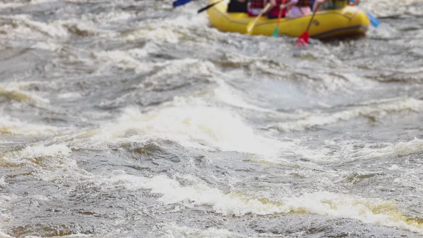 Rafting in whitewater, extreme water sports on water rapids, kayaking and canoeing tour in a mountain river,  water sports team, red and yellow raft boat full of tourists in a summer day, slow motion