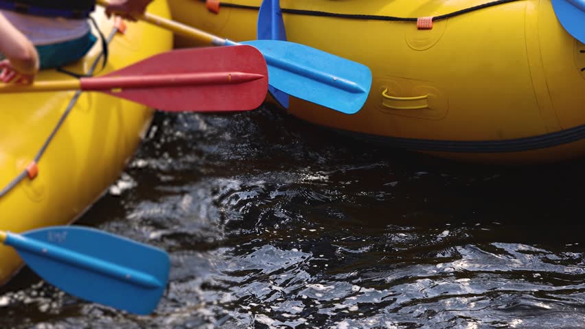 Rafting in whitewater, extreme water sports on water rapids, kayaking and canoeing tour in a mountain river,  water sports team, red and yellow raft boat full of tourists in a summer day, slow motion