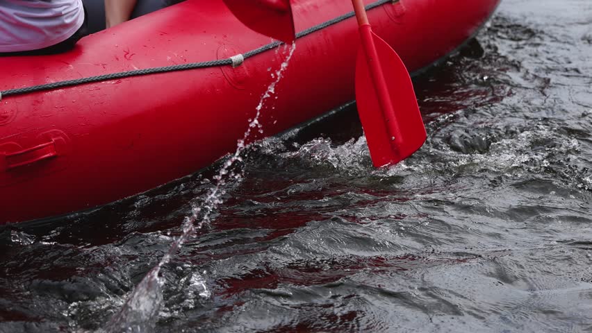 Rafting in whitewater, extreme water sports on water rapids, kayaking and canoeing tour in a mountain river,  water sports team, red and yellow raft boat full of tourists in a summer day, slow motion