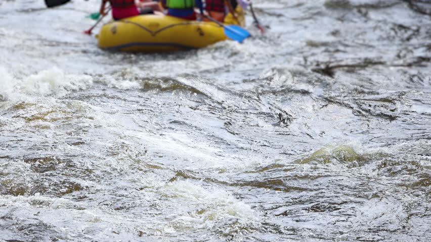 Rafting in whitewater, extreme water sports on water rapids, kayaking and canoeing tour in a mountain river,  water sports team, red and yellow raft boat full of tourists in a summer day, slow motion