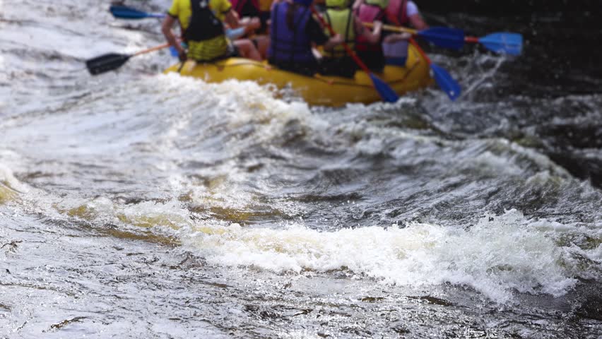 Rafting in whitewater, extreme water sports on water rapids, kayaking and canoeing tour in a mountain river,  water sports team, red and yellow raft boat full of tourists in a summer day, slow motion