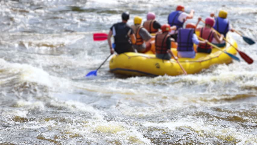 Rafting in whitewater, extreme water sports on water rapids, kayaking and canoeing tour in a mountain river,  water sports team, red and yellow raft boat full of tourists in a summer day, slow motion