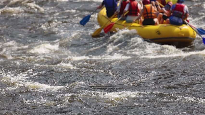 Rafting in whitewater, extreme water sports on water rapids, kayaking and canoeing tour in a mountain river,  water sports team, red and yellow raft boat full of tourists in a summer day, slow motion