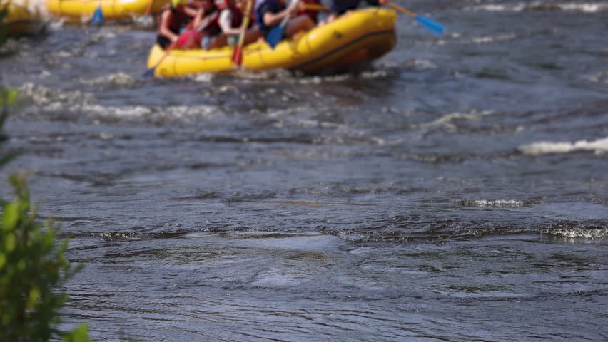 Rafting in whitewater, extreme water sports on water rapids, kayaking and canoeing tour in a mountain river,  water sports team, red and yellow raft boat full of tourists in a summer day, slow motion