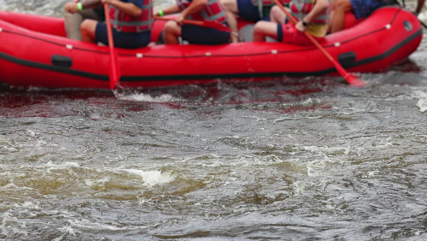 Rafting in whitewater, extreme water sports on water rapids, kayaking and canoeing tour in a mountain river,  water sports team, red and yellow raft boat full of tourists in a summer day, slow motion