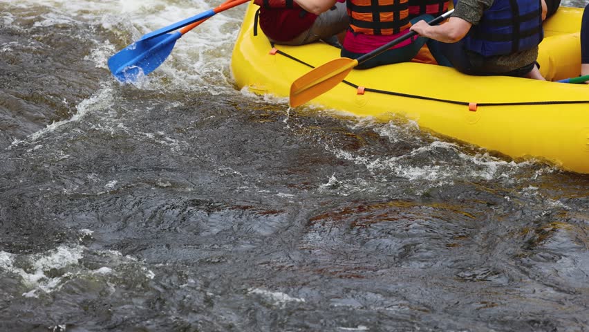 Rafting in whitewater, extreme water sports on water rapids, kayaking and canoeing tour in a mountain river,  water sports team, red and yellow raft boat full of tourists in a summer day, slow motion