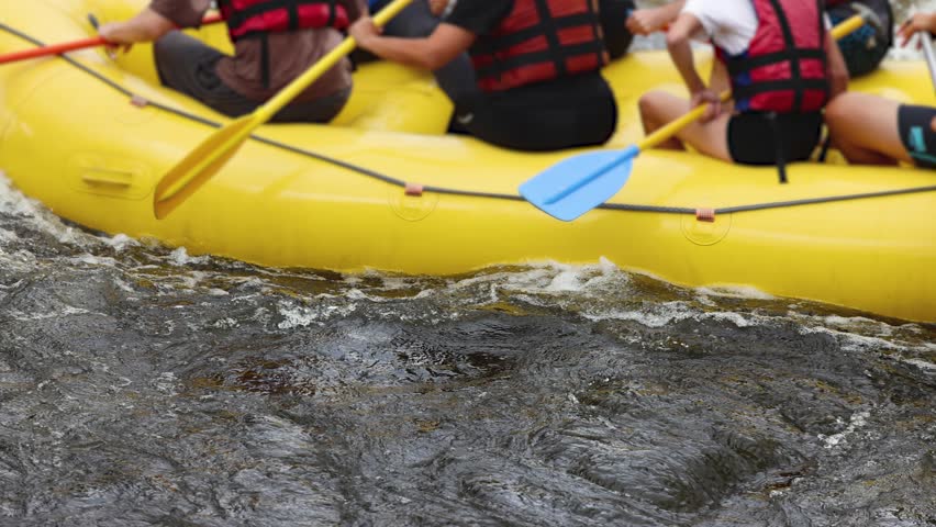Rafting in whitewater, extreme water sports on water rapids, kayaking and canoeing tour in a mountain river,  water sports team, red and yellow raft boat full of tourists in a summer day, slow motion