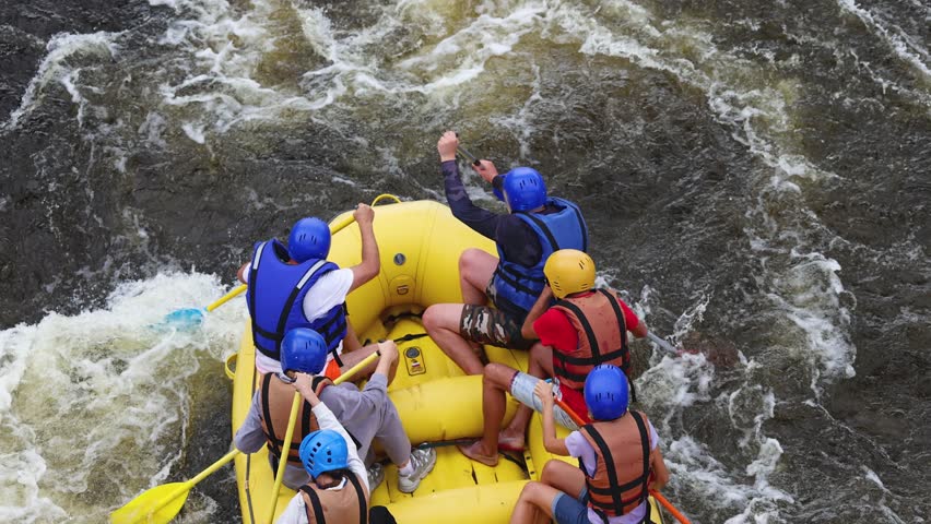 Rafting in whitewater, extreme water sports on water rapids, kayaking and canoeing tour in a mountain river,  water sports team, red and yellow raft boat full of tourists in a summer day, slow motion