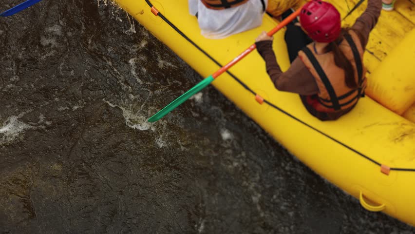 Rafting in whitewater, extreme water sports on water rapids, kayaking and canoeing tour in a mountain river,  water sports team, red and yellow raft boat full of tourists in a summer day, slow motion