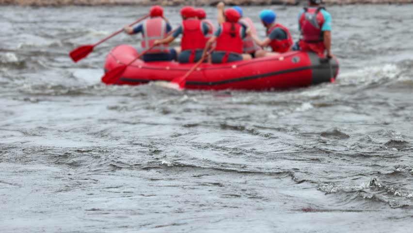 Rafting in whitewater, extreme water sports on water rapids, kayaking and canoeing tour in a mountain river,  water sports team, red and yellow raft boat full of tourists in a summer day, slow motion