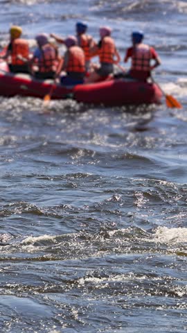 Rafting in whitewater, extreme water sports on water rapids, kayaking and canoeing tour in a mountain river,  water sports team, red and yellow raft boat full of tourists in a summer day, slow motion