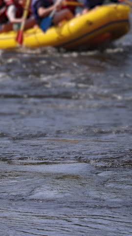 Rafting in whitewater, extreme water sports on water rapids, kayaking and canoeing tour in a mountain river,  water sports team, red and yellow raft boat full of tourists in a summer day, slow motion