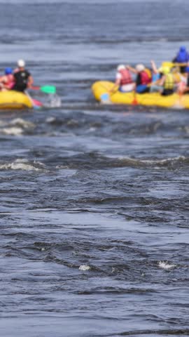 Rafting in whitewater, extreme water sports on water rapids, kayaking and canoeing tour in a mountain river,  water sports team, red and yellow raft boat full of tourists in a summer day, slow motion
