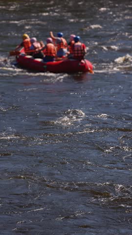 Rafting in whitewater, extreme water sports on water rapids, kayaking and canoeing tour in a mountain river,  water sports team, red and yellow raft boat full of tourists in a summer day, slow motion