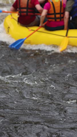 Rafting in whitewater, extreme water sports on water rapids, kayaking and canoeing tour in a mountain river,  water sports team, red and yellow raft boat full of tourists in a summer day, slow motion