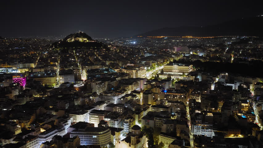 Panoramic shot of Syntagma square in Athens, Greece during night. Hellenic Parliament in view and Lycabettus Hill in the background
