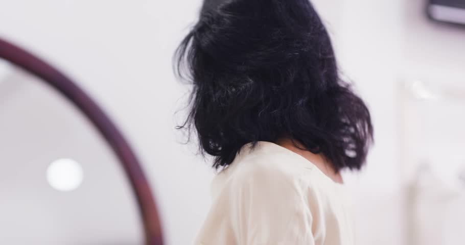 Young woman admiring her reflection while shopping in bright fashion boutique. Soft natural tones and elegant styling. Perfect for lifestyle campaigns, retail ads, and fashion content.