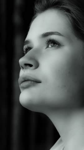 A black and white portrait of a thoughtful young girl gazing away. Vertical video.