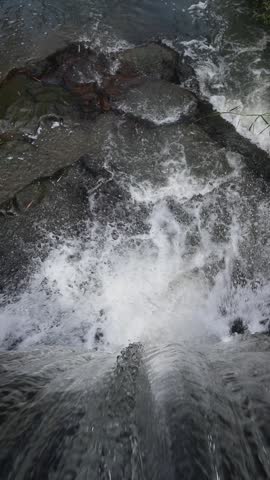 Majestic Waterfall Flow: Top-Down Rushing Water 

A high-angle, close-up shot of crystal clear river water cascading over dark rocks, creating white foam and a powerful sense of natural movement.