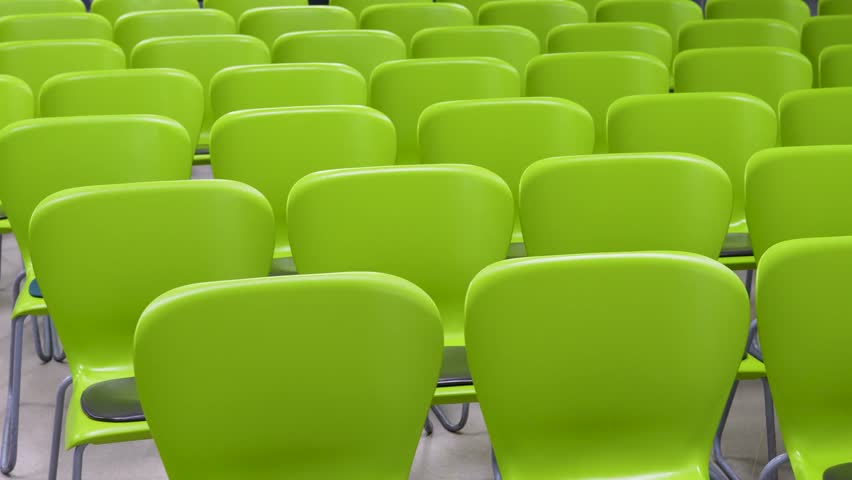 Rows of Modern Lime Green Plastic Chairs in Empty Hall. Rows of green plastic chairs in a lecture hall or waiting area. Minimalist seating arrangement for events, conferences, or public spaces