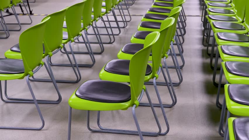 Rows of Modern Lime Green Plastic Chairs in Empty Hall. Rows of green plastic chairs in a lecture hall or waiting area. Minimalist seating arrangement for events, conferences, or public spaces