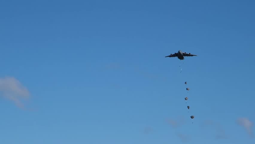A mass tactical drop by US Army paratroopers over a landing zone in Germany. Airborne troops descend from the sky using T-11 parachutes during a large-scale NATO military exercise in Europe.