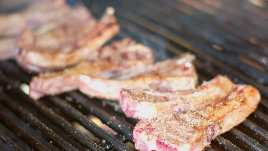 Sizzling seasoned lamb chops on barbecue grilled over gas flame, rack focus