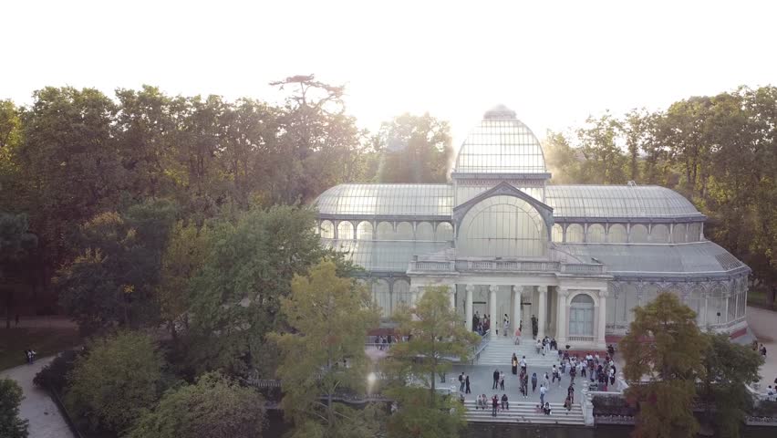 Aerial view of The crystal palace (Palacio de Cristal) located in El Retiro Park (Parque de El Retiro) Madrid, Spain, is a UNESCO world heritage site. View against blue sky at autumn