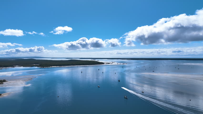 Aerial over speeding boat through Great Sandy Strait, anchorage and lush isles