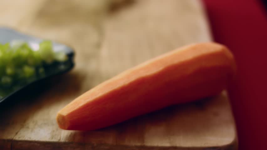 Close up of cutting a raw carrot on a wooden cutting board