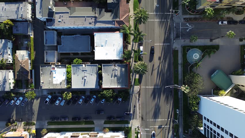 Coastal block geometry near Ocean Blvd, Hermosa Ave with dense residential parcels arranged in tight urban grid. Sunlit roofs, palm trees street, varied materials layered textures, Long Beach, CA. USA
