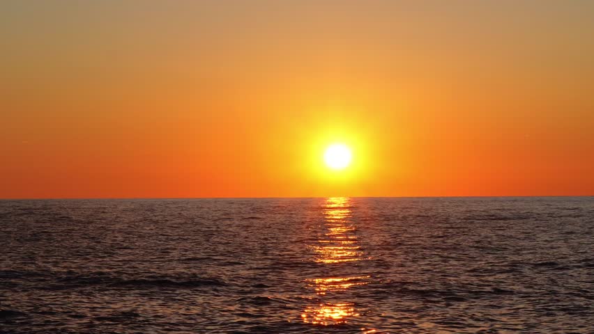 Sunset view over the ocean with vibrant colors and clouds reflecting sunlight