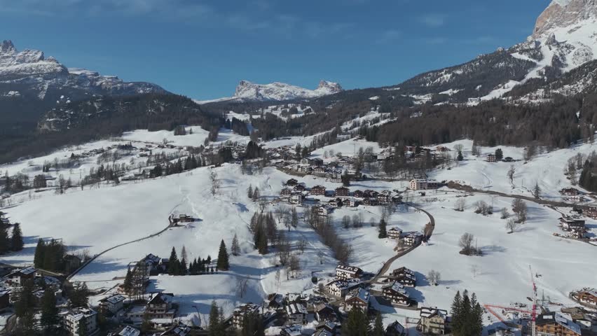 Alpine town and surrounding Dolomites mountains under a blue sky. Cortina d