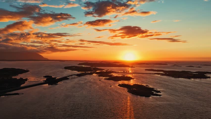 Atlantic Ocean Road, famous bridge between islands with sunset sky reflecting on calm water. Norway time lapse aerial
