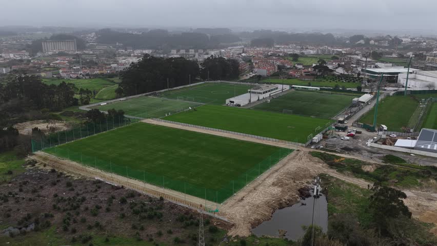 Drone shot of football and soccer fields with person cutting grass on a machine.