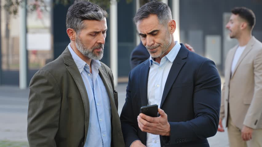 Two colleagues businessmen are discussing work looking at a mobile phone app