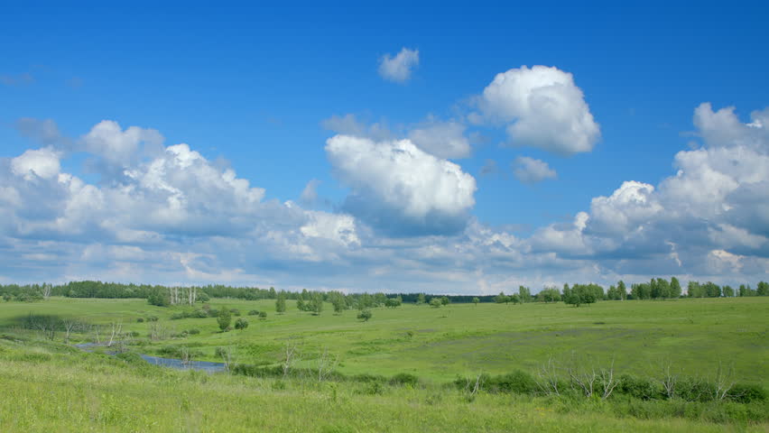 A Beautiful, Serene Green Landscape Beneath a Vast Blue Sky with Fluffy Clouds Floating