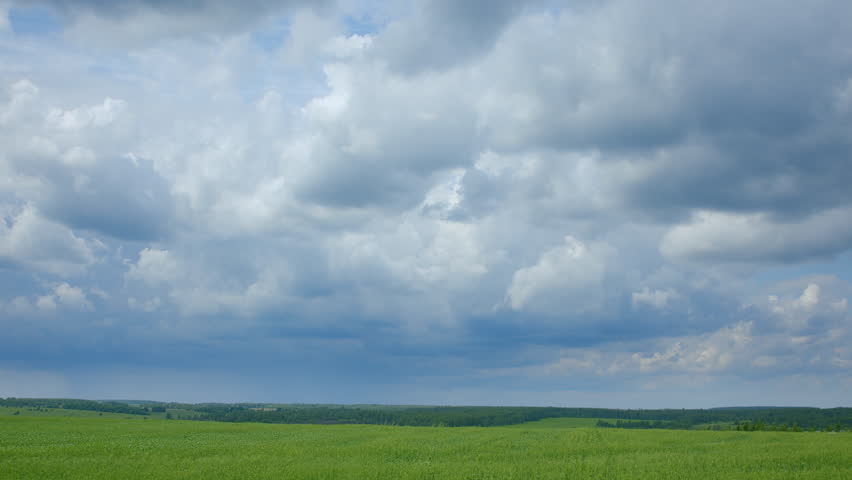 A Dramatic Cloudy Sky Stretches Over Expansive Green Fields in the Countryside Landscape